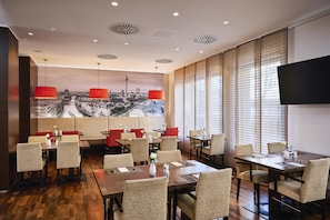 A restaurant with wooden flooring, red pendant lights, and a large cityscape mural on the wall. - NH Berlin Potsdamer Platz (Berlin)