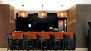 A modern kitchen with a central island, black bar stools, and pendant lighting. - NH Campo De Gibraltar (Los Barrios)