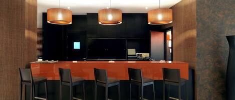 Una cocina moderna con una isla central, taburetes negros tipo bar e iluminación colgante.