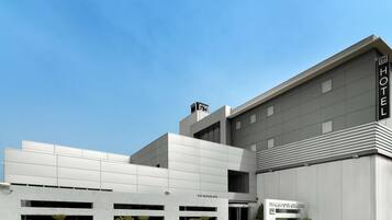 A modern hotel with a flat facade, multiple entry points, and potted plants in front.