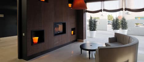 Un vestíbulo moderno con una pared de madera oscura, iluminación empotrada, un sofá grande, una mesa de centro y plantas en macetas.