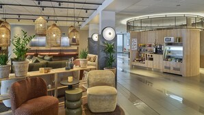 A modern hotel lobby with a seating area, a reception desk, and a food service counter. - Scandic Karlskrona (Karlskrona)