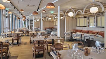 Um restaurante espaçoso com várias áreas de refeições, mesas e cadeiras de madeira.