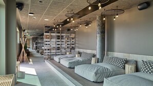 A modern spa area with seating, a wooden bookshelf, and a large pillar. - Scandic Karlskrona (Karlskrona)