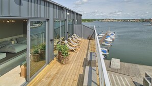 A modern balcony with wooden flooring, glass doors, and lounge chairs. - Scandic Karlskrona (Karlskrona)