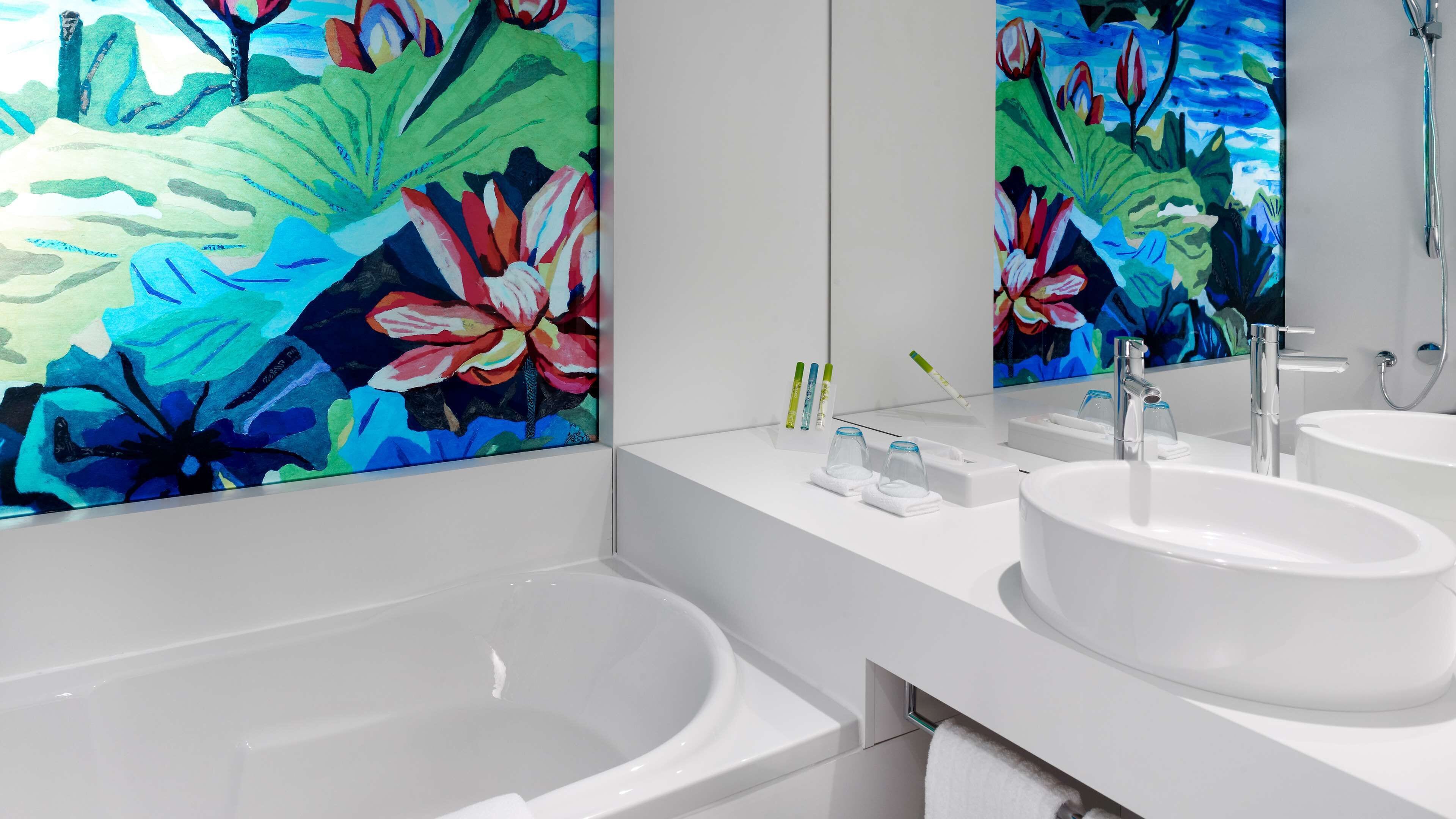Un baño moderno con dos lavamanos, una bañera y un espejo grande.