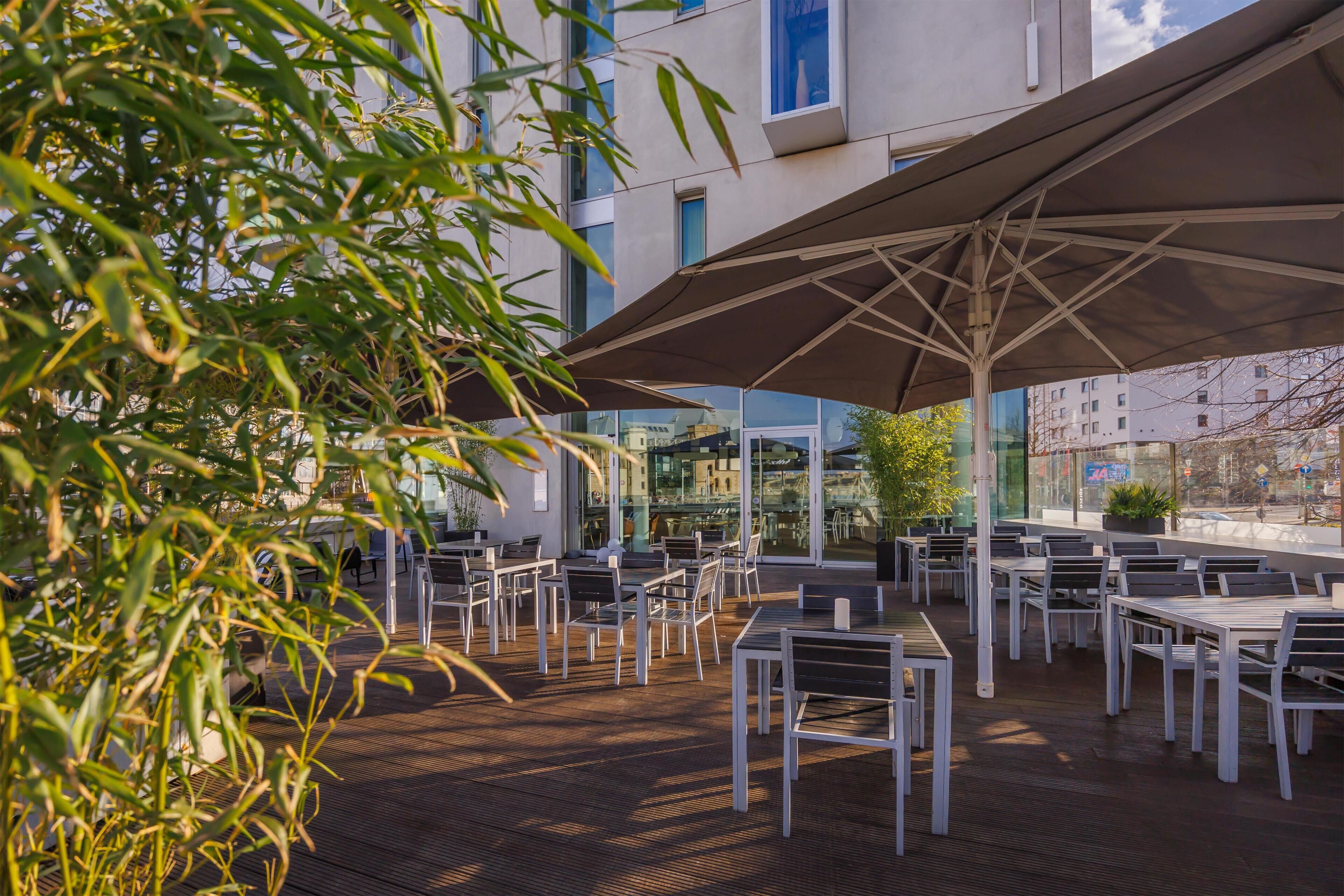 An outdoor patio with tables and chairs, large umbrellas, and a wooden deck.