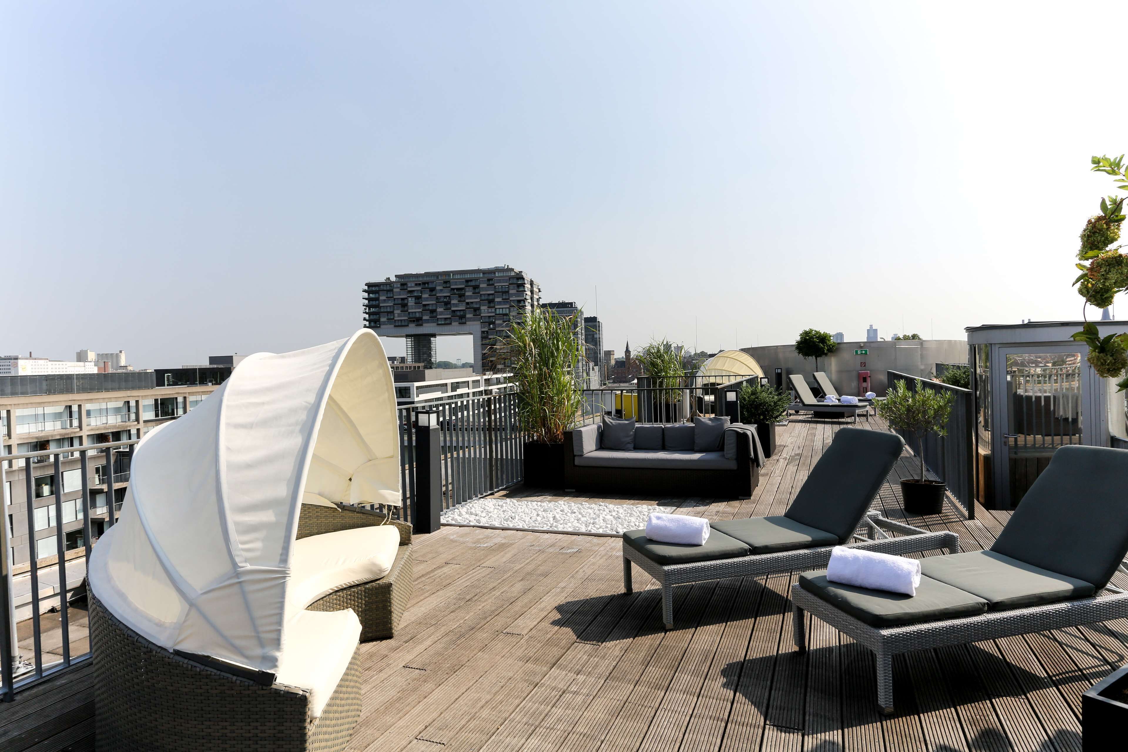 Een terras op het dak met loungestoelen, een bank en een zonnescherm.