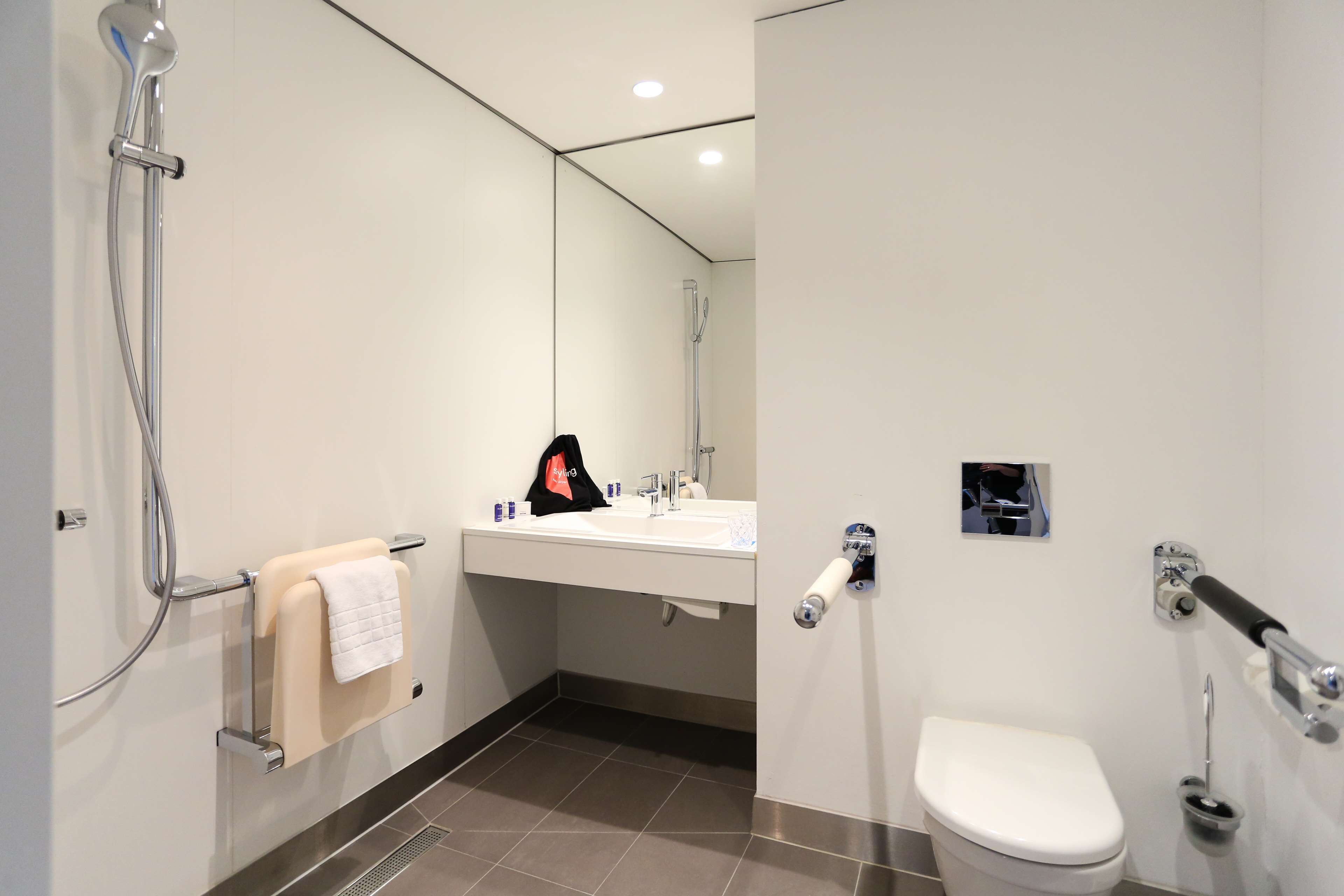 A modern bathroom with a shower, sink, and toilet.