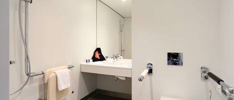 A modern bathroom with a shower, sink, and toilet.