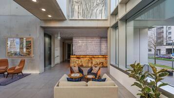A modern lobby with a sofa set, a reception desk, and a large wall mural.