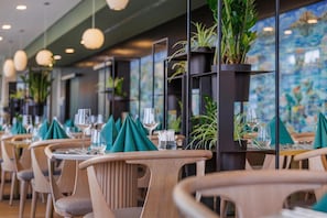 Ein Restaurant mit Holzkreisen, Tischen mit grünen Servietten und Blumentöpfen.