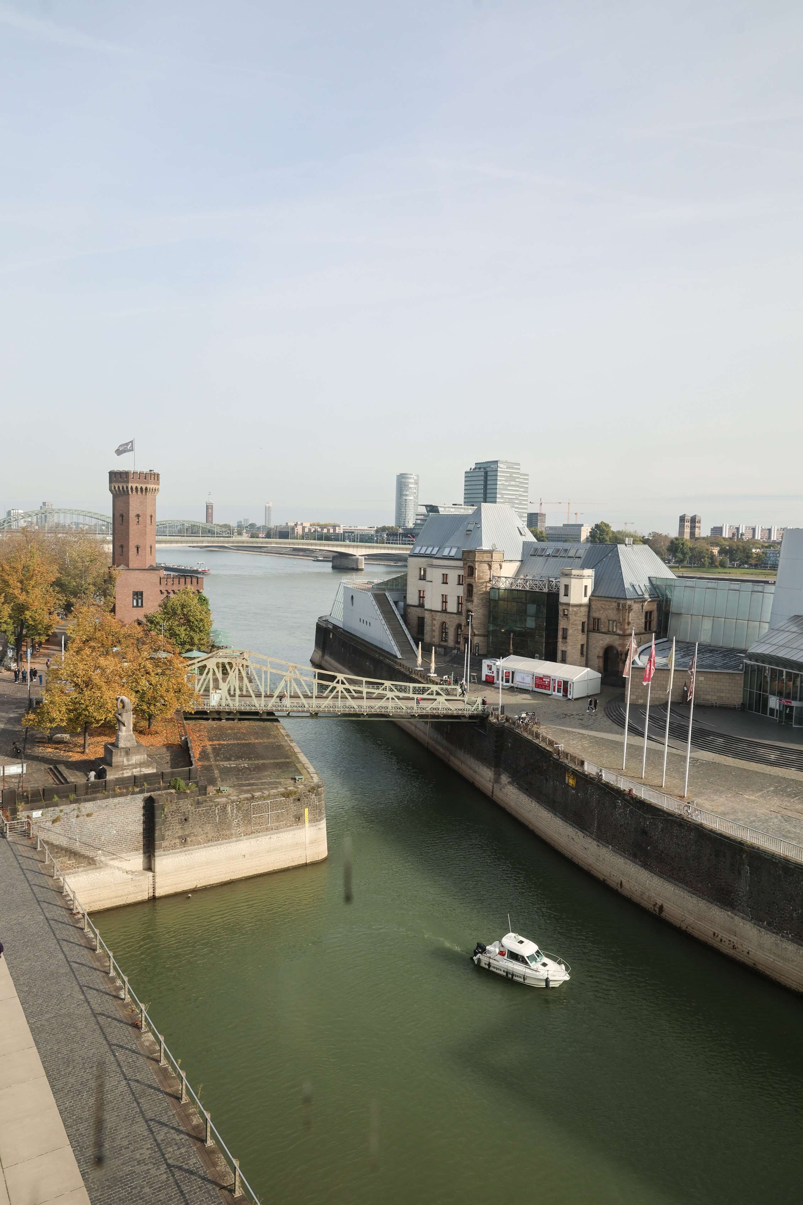 Un río con una barca, una torre y un edificio moderno con fachada de vidrio.