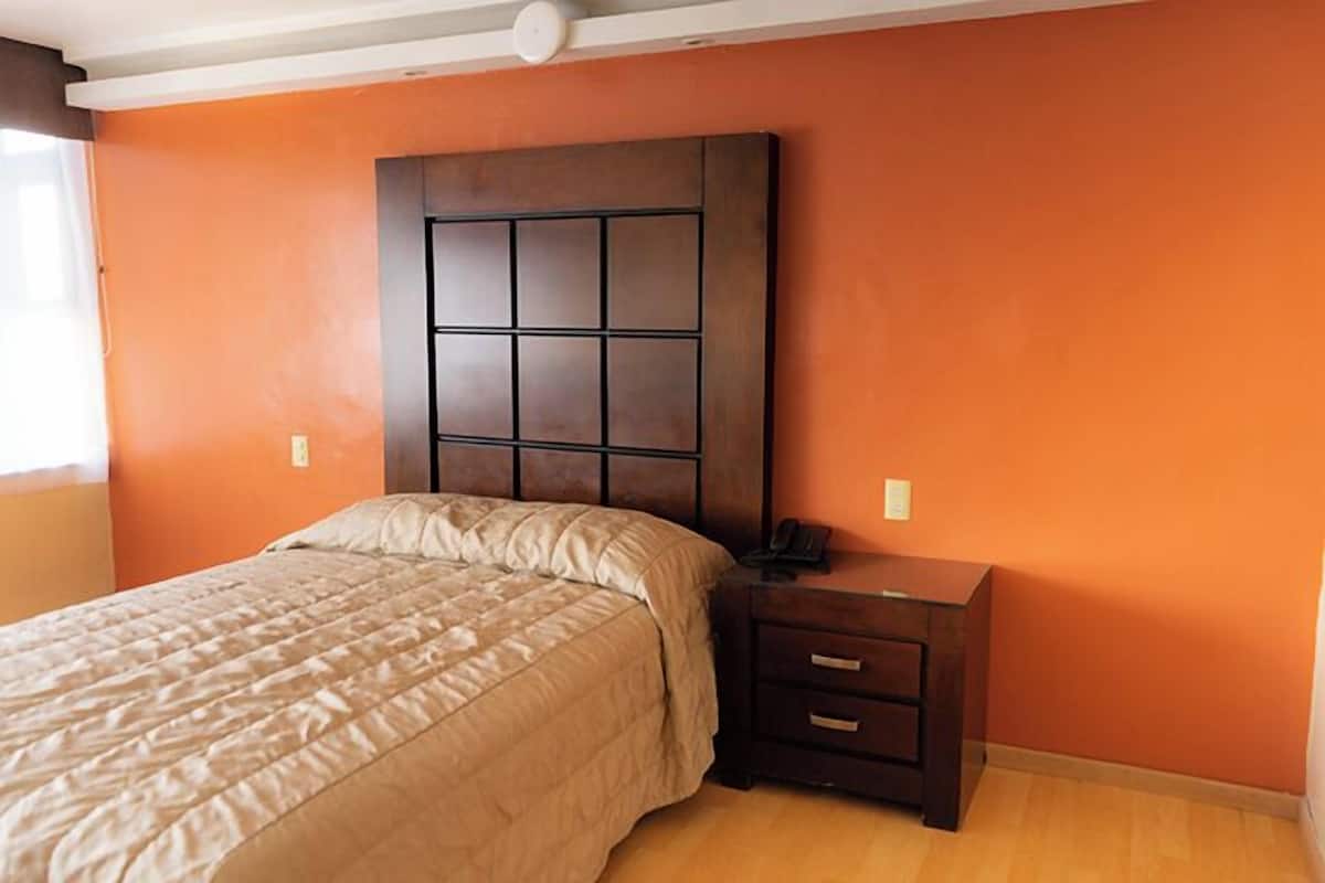Un dormitorio con una cama grande, una mesita de noche y un cabecero con diseño de cuadrícula.