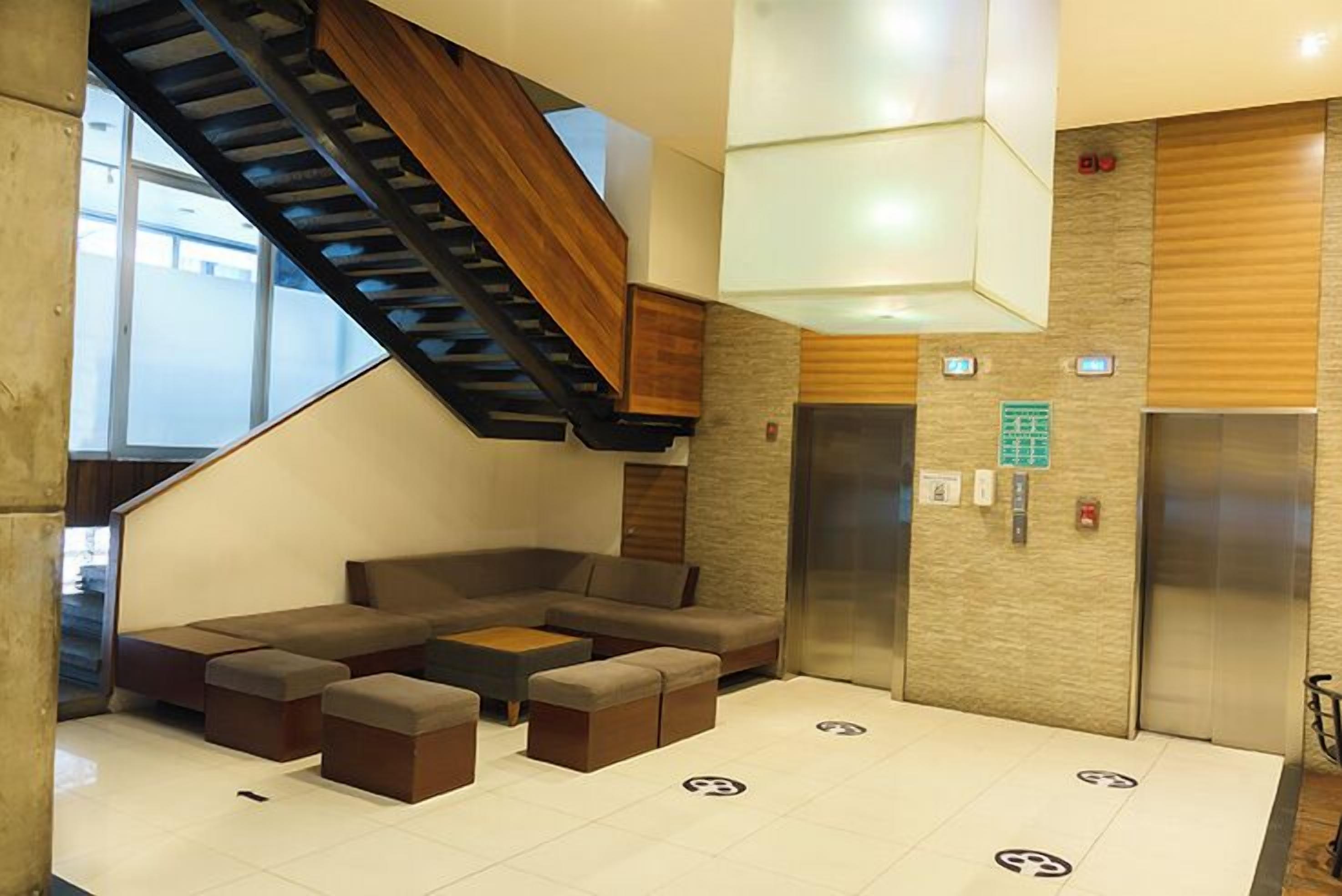 Um hall moderno com escada, sofá de canto e elevador.