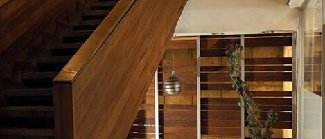 Una escalera moderna con barandillas de madera y una planta en maceta.