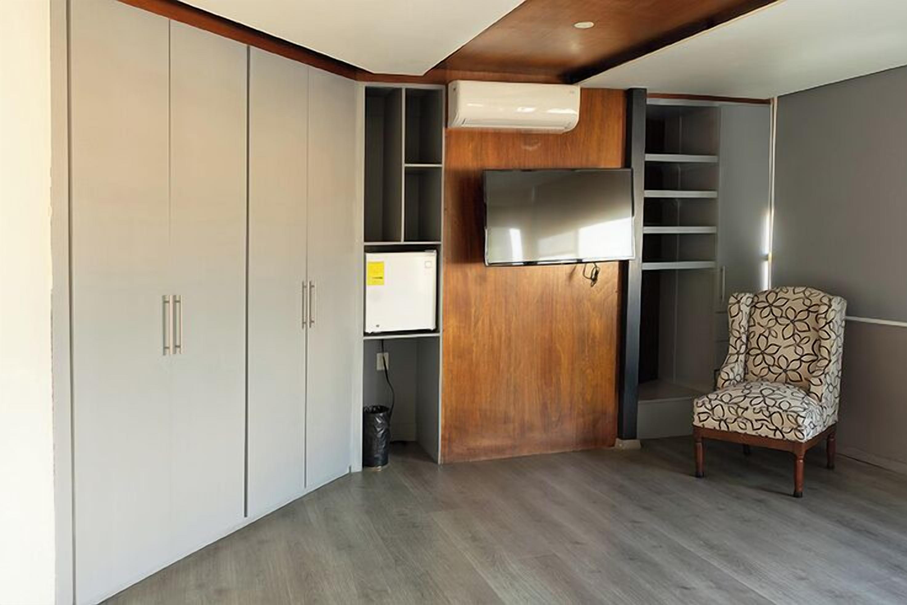 Un espacio habitable compacto con armarios empotrados, una pared de acento de madera y un sillón estampado.