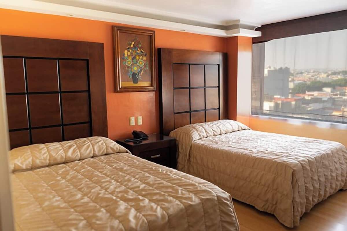 Habitación de hotel con dos camas, vista a la ciudad y un cuadro en la pared.