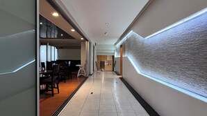 A modern hallway with a glass wall on one side, a patterned wall on the other, and a tiled floor. - Hotel Gilfer Puebla Centro Histórico (Puebla)