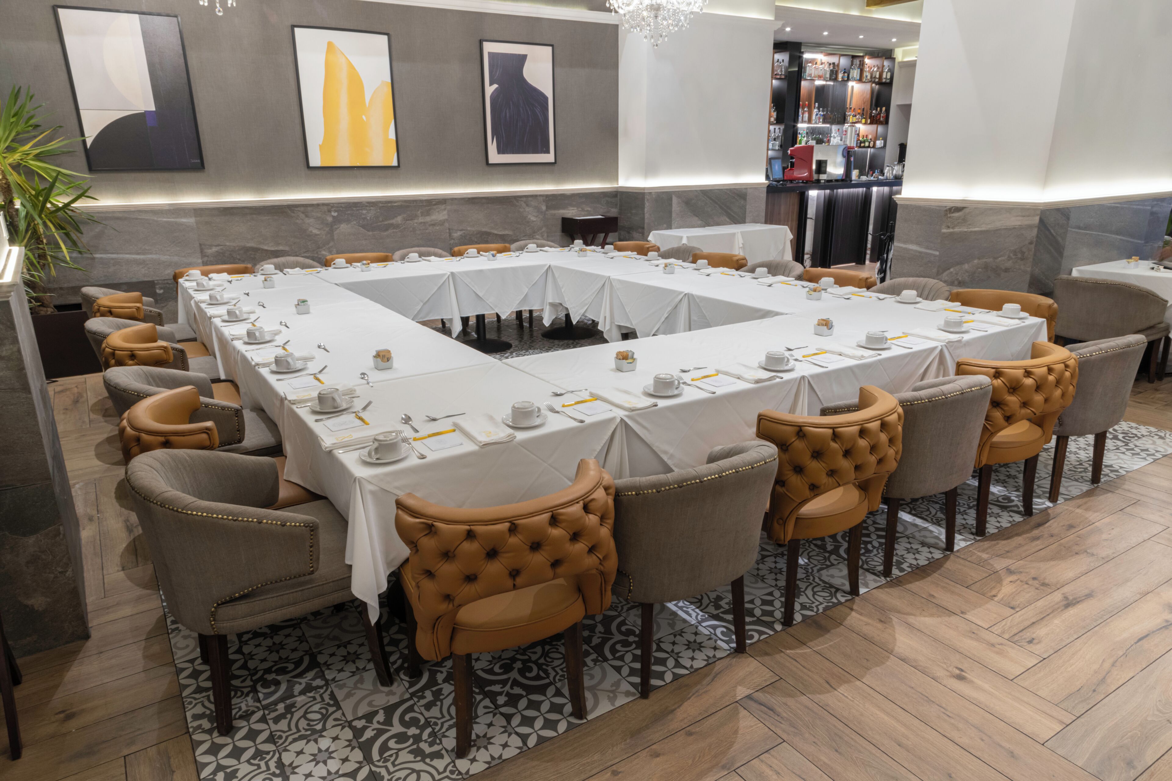 A conference room with a long table, chairs, and a bar area in the background.