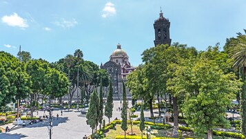 Una plaza con un edificio destacado que presenta una cúpula y una torre, rodeada de árboles y espacio abierto.