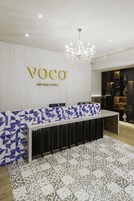 Una recepción de diseño moderno, con un frente de baldosas azules y blancas estampadas y una lámpara de araña colgando arriba.