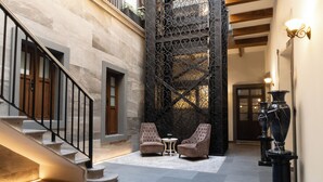 Un hall d’entrée spacieux avec un escalier, deux fauteuils, une petite table et des vases décoratifs.