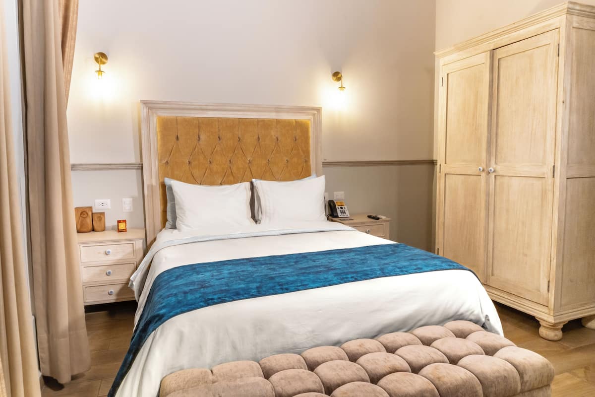 A neatly arranged bedroom with a large bed, bedside tables, a wardrobe, and a bedside lamp.