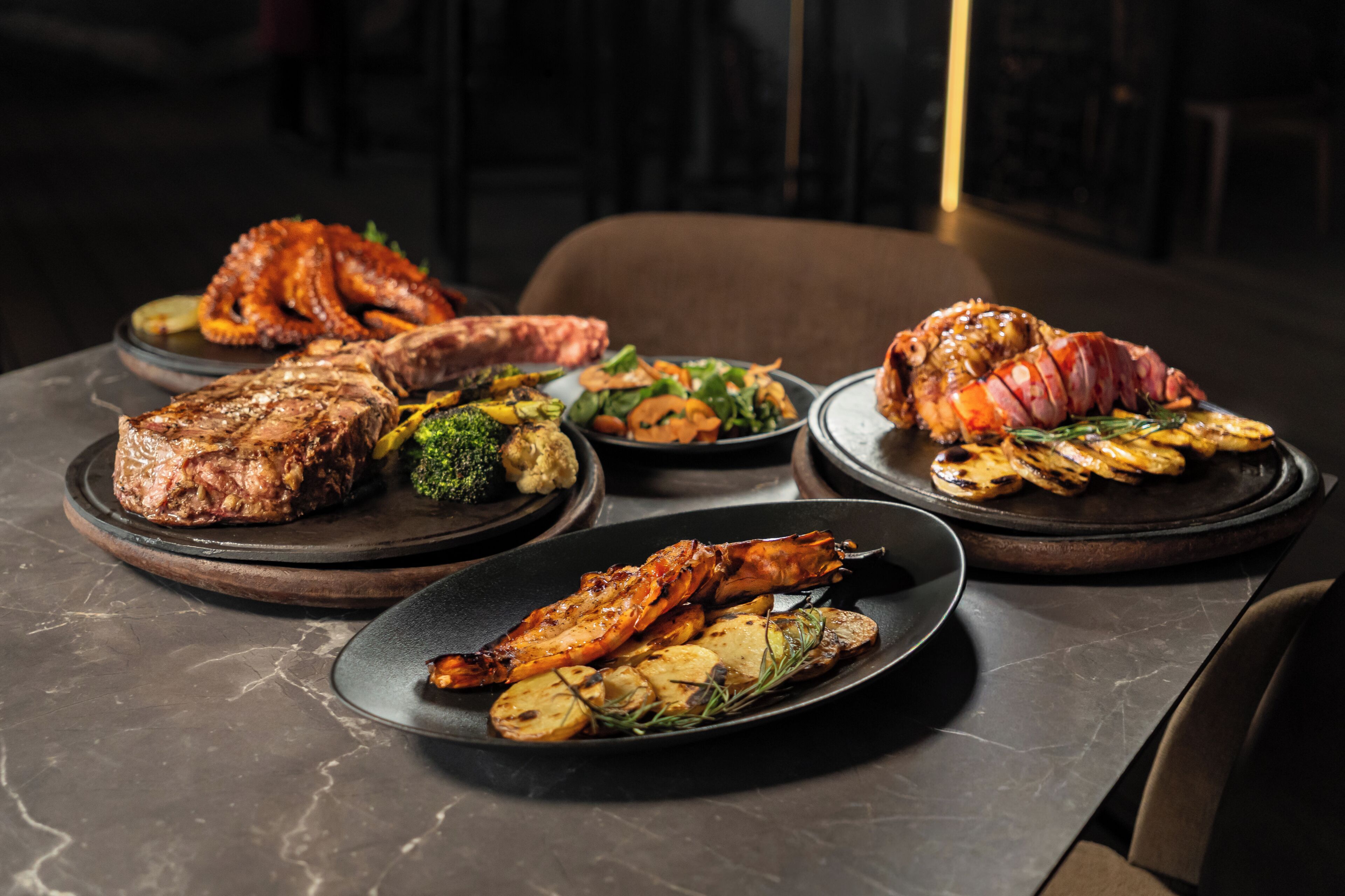 A dining table with various dishes including grilled meats and vegetables.