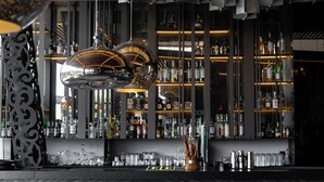 Un bar au design moderne, avec une variété de bouteilles d’alcool et de verres exposés sur des étagères.