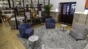 Un hall d’entrée avec des espaces où s’asseoir, une plante décorative et un mur orné d’un motif.