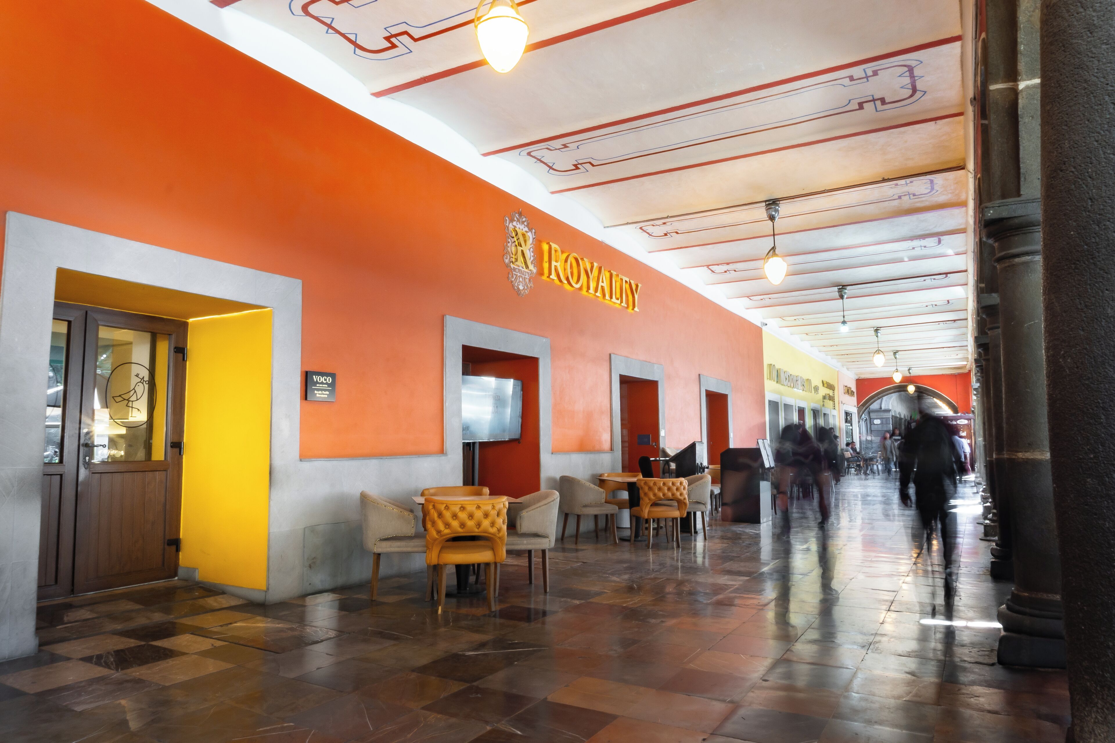 A hotel corridor with orange walls, a 'ROYALTY' sign, and a checkered floor.