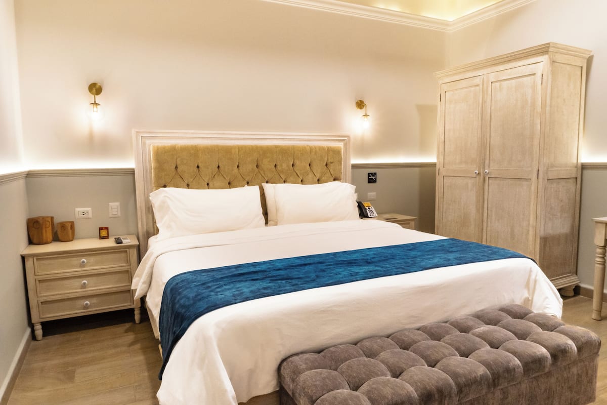 A neatly arranged bedroom with a large bed, bedside tables, a wardrobe, and a bench.
