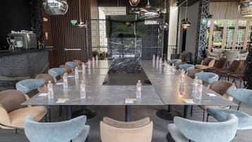 Un salón de conferencias con una mesa larga, sillas, botellas de agua y un diseño interior moderno.