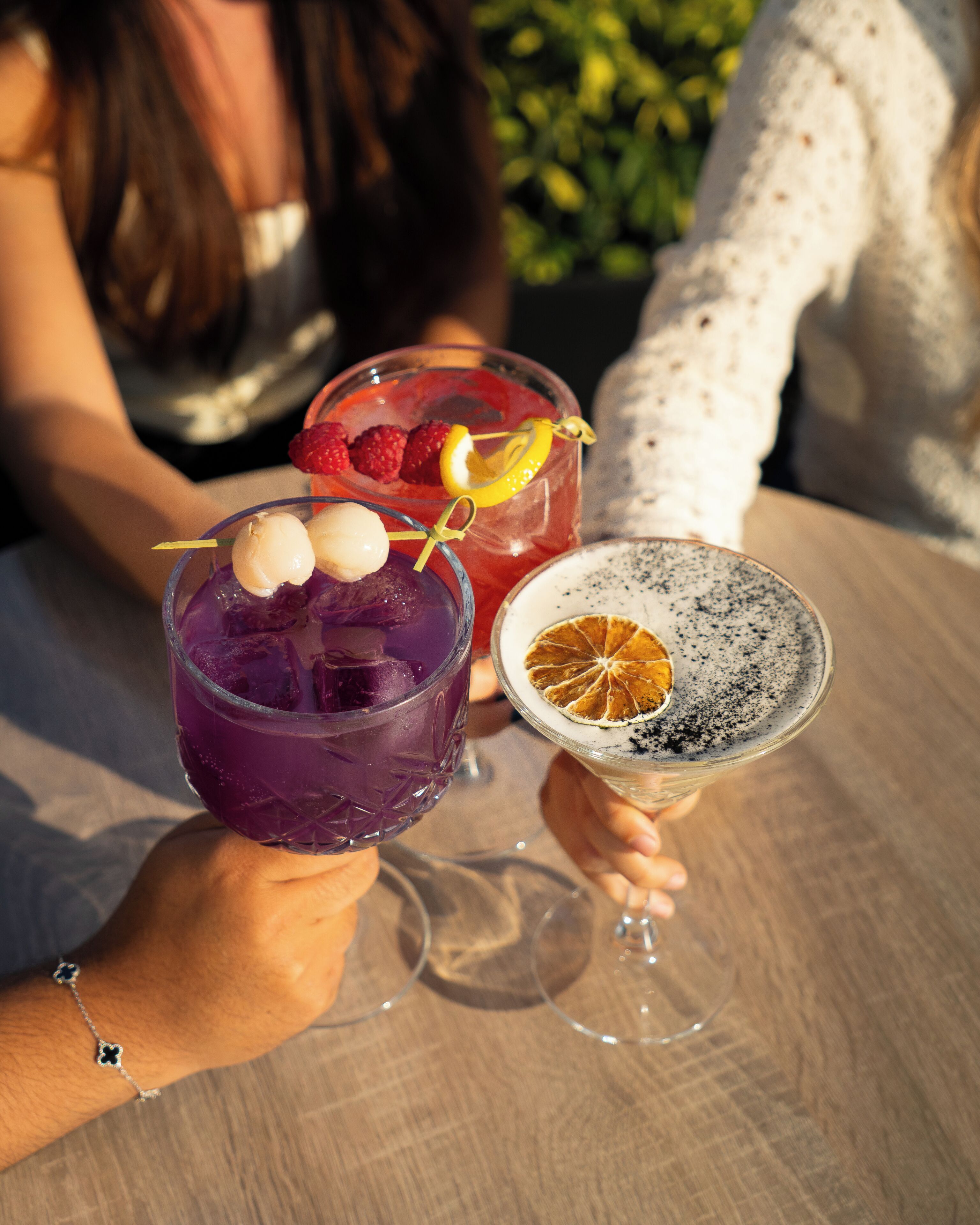Tres bebidas con adornos, sostenidas por personas en una mesa.