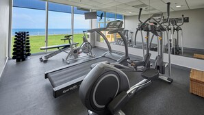 Un gimnasio con equipo cardiovascular, máquinas de pesas y mancuernas.