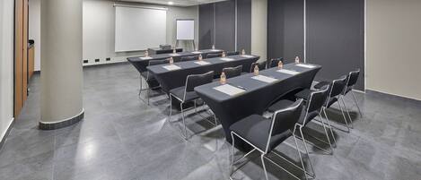 A conference room with a large table, chairs, a projector screen, and a whiteboard.