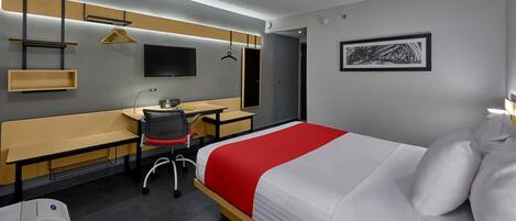 A hotel room with a bed, a desk, a chair, a bench, a TV, a coat rack, and a framed picture on the wall.