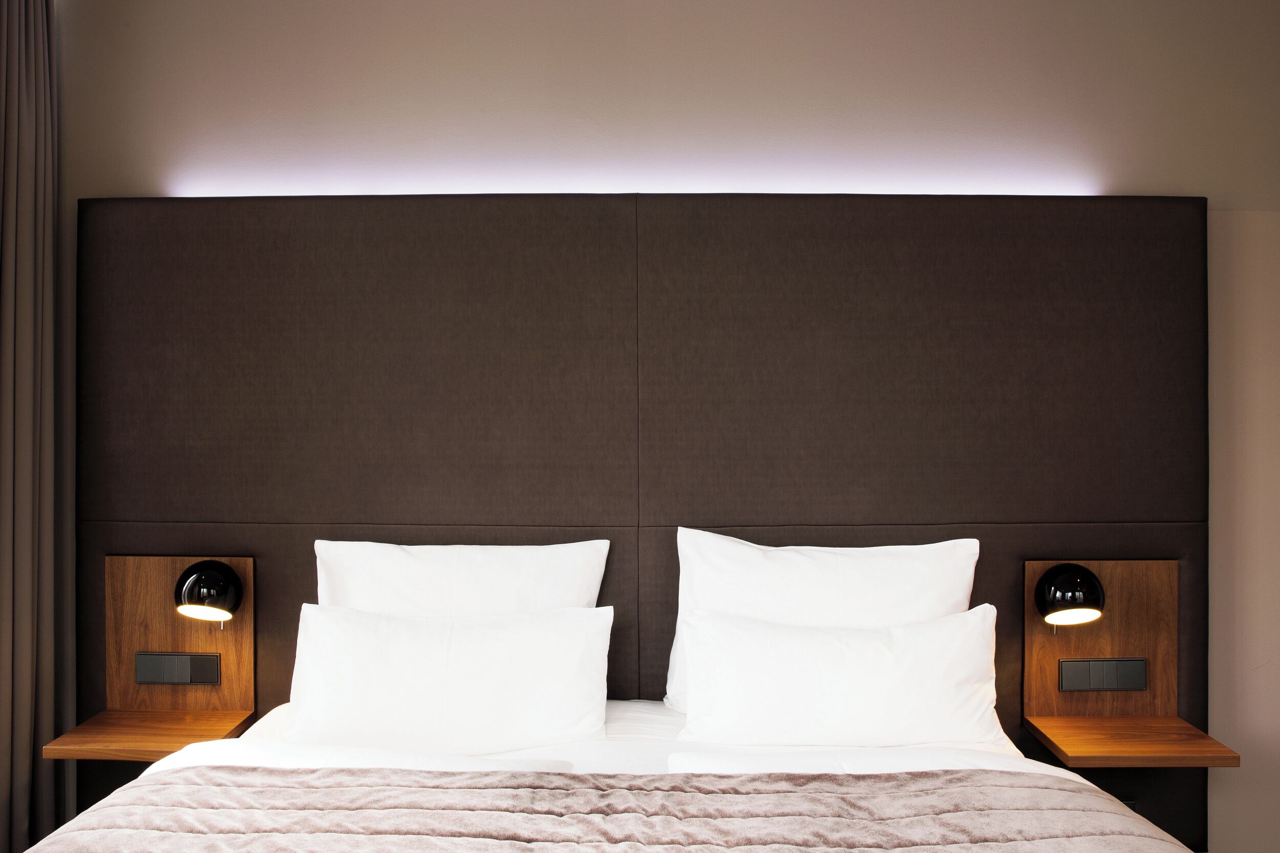 Una cama doble con dos mesitas de noche, cada una con una lámpara.