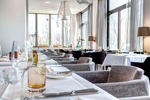 Ein Restaurant mit mehreren Tischen, jeweils gedeckt mit weißen Tischdecken, Tellern und Gläsern.