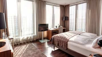 A hotel room with a bed, a desk, a TV, and a phone.