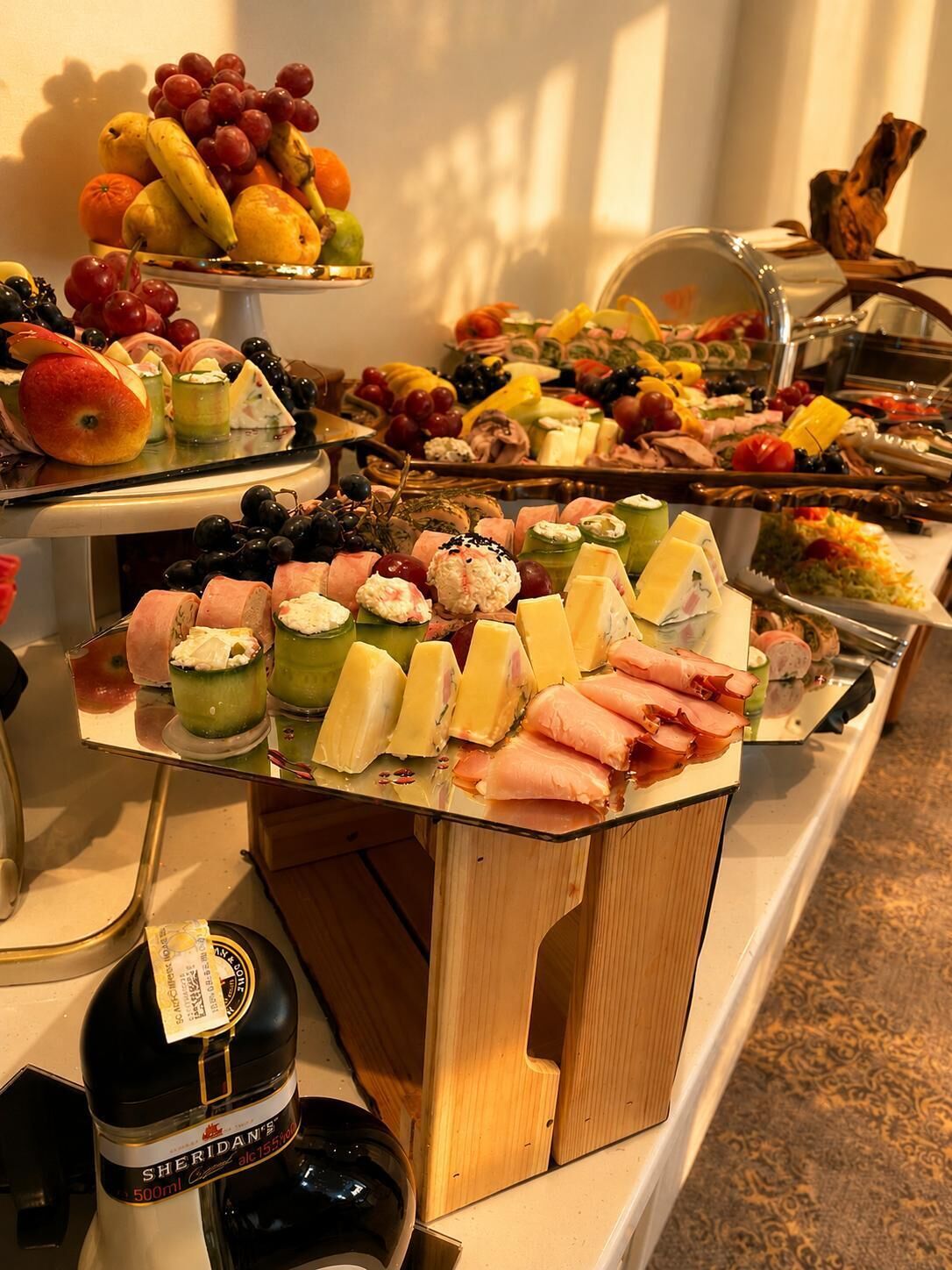 A buffet with various food items including fruits, cheeses, and meats.