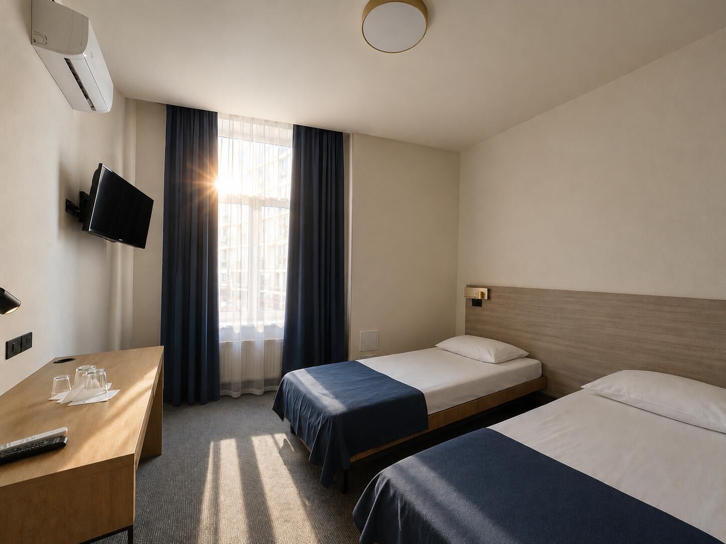 Habitación de hotel con dos camas, un escritorio, un televisor y un aire acondicionado.