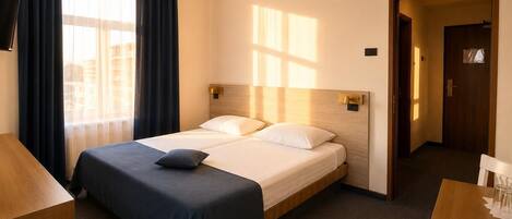 Habitación de hotel con cama, escritorio y televisor.
