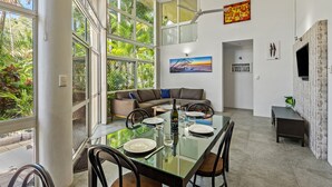 A modern dining area with a glass table, chairs, and a sofa.