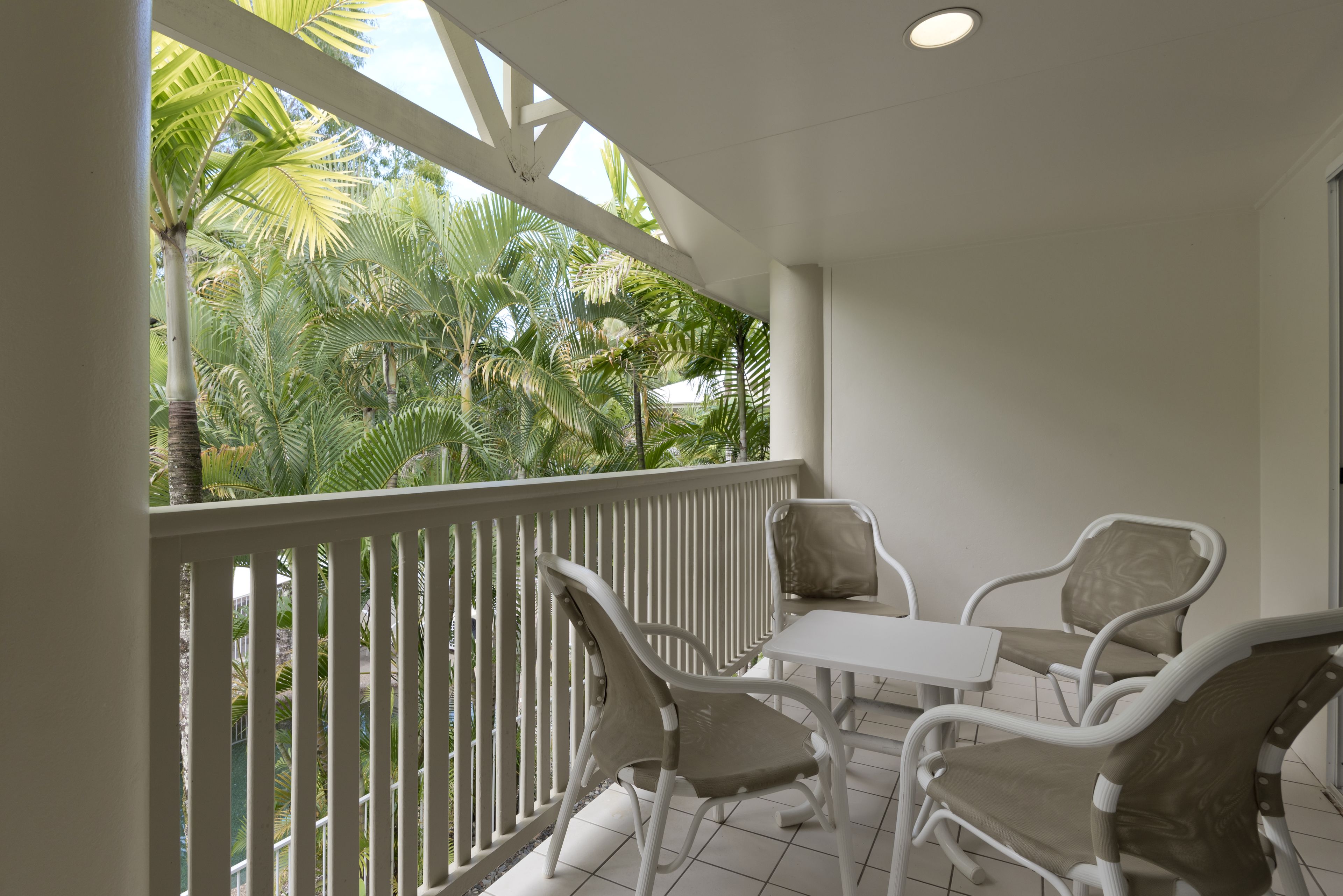 A balcony with white railings, a table, and four chairs.