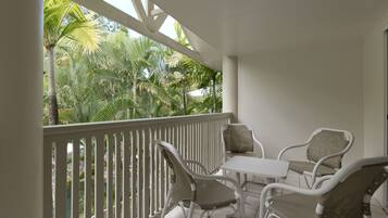 A balcony with white railings, a table, and four chairs.