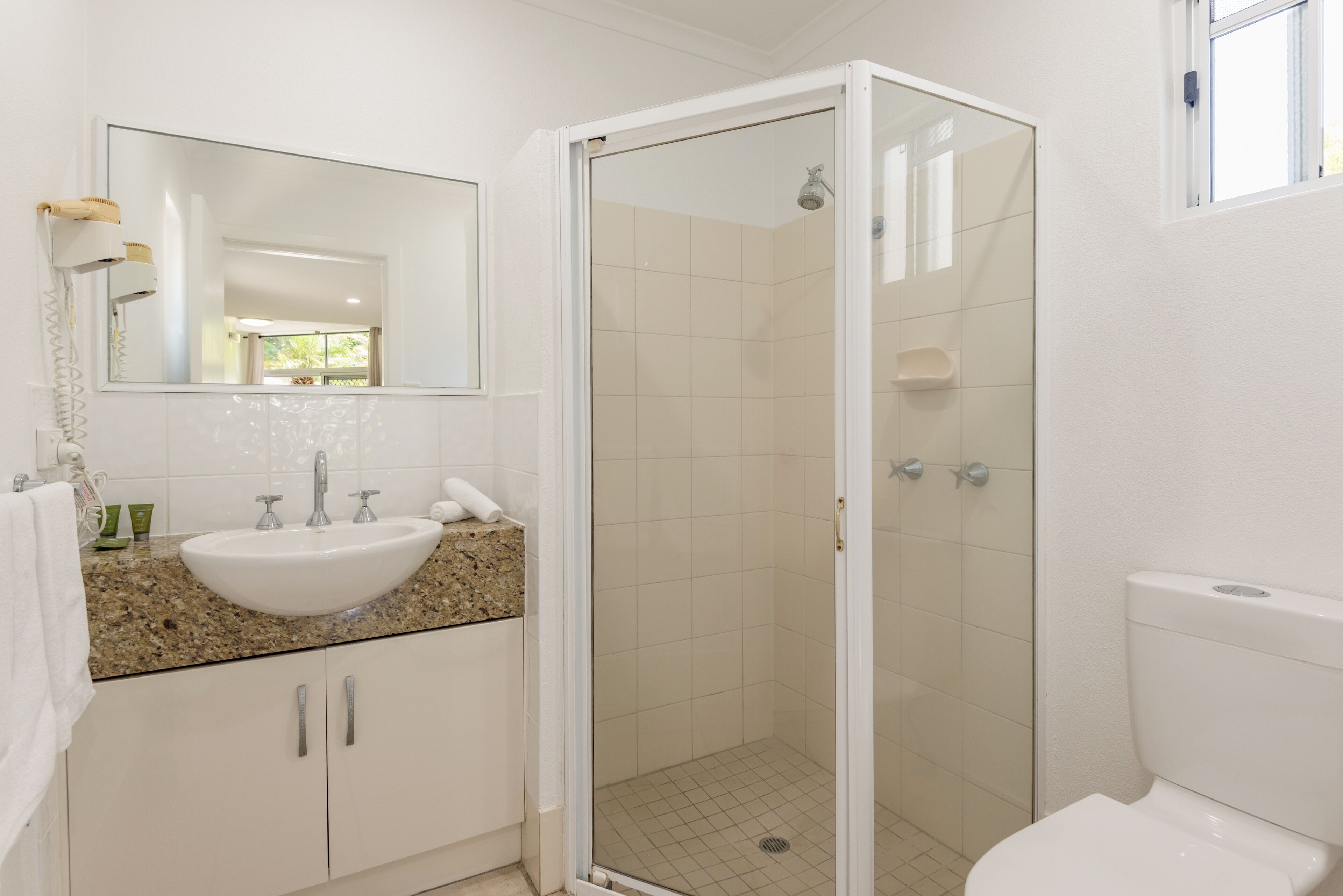 A bathroom with a white sink, mirror, and shower.