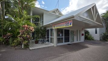 A reception area with a sign for tour bookings, a covered outdoor seating area, and a building with a white facade.