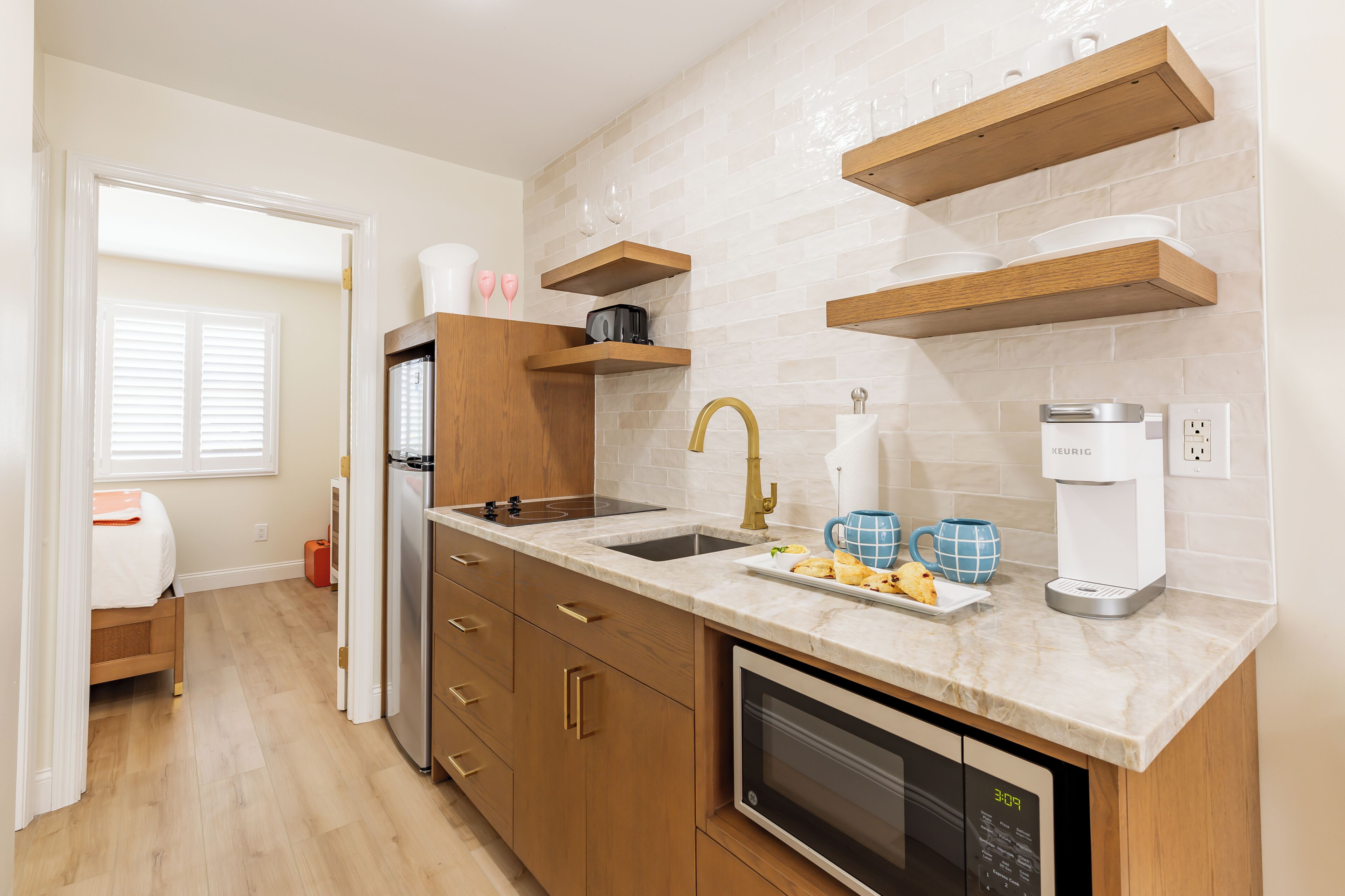 A modern kitchen with wooden cabinets, a built-in oven, a sink, and a coffee maker.